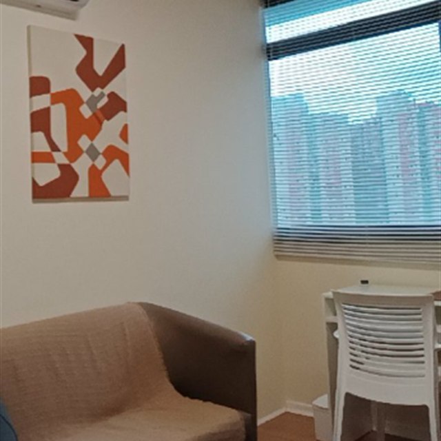 Ambiente de atendimento com poltrona, quadro e luz natural.